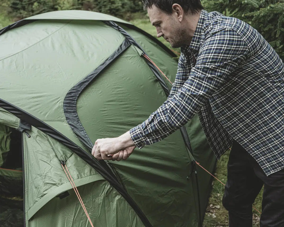 Kampeerders met de Easy Camp Lomsdal 3 Tent aan de rand van een meer, ideaal voor een ontspannen natuurervaring.